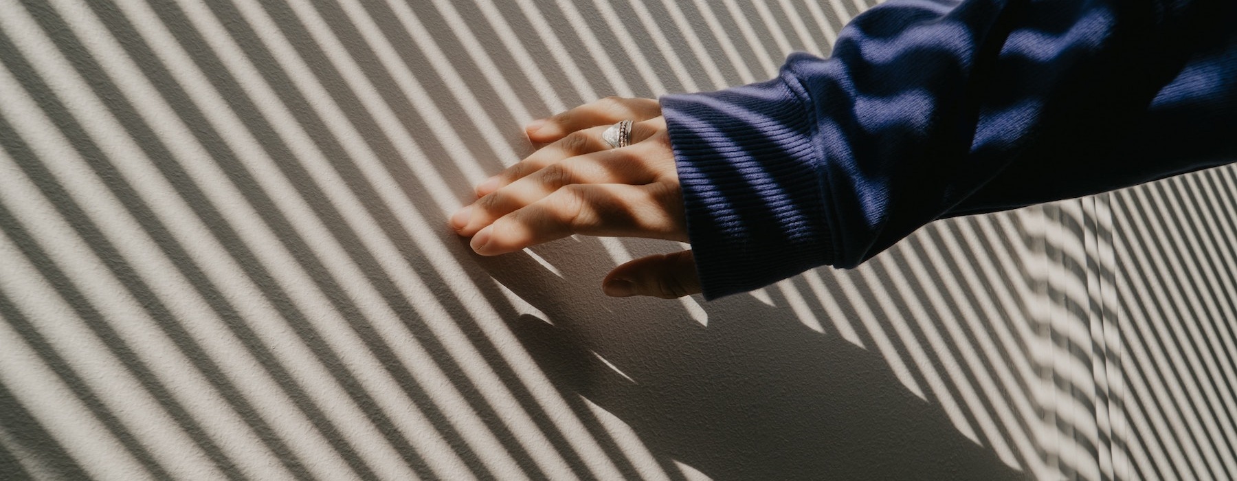 lifestyle image of a hand being slid across a sunset-lit wall